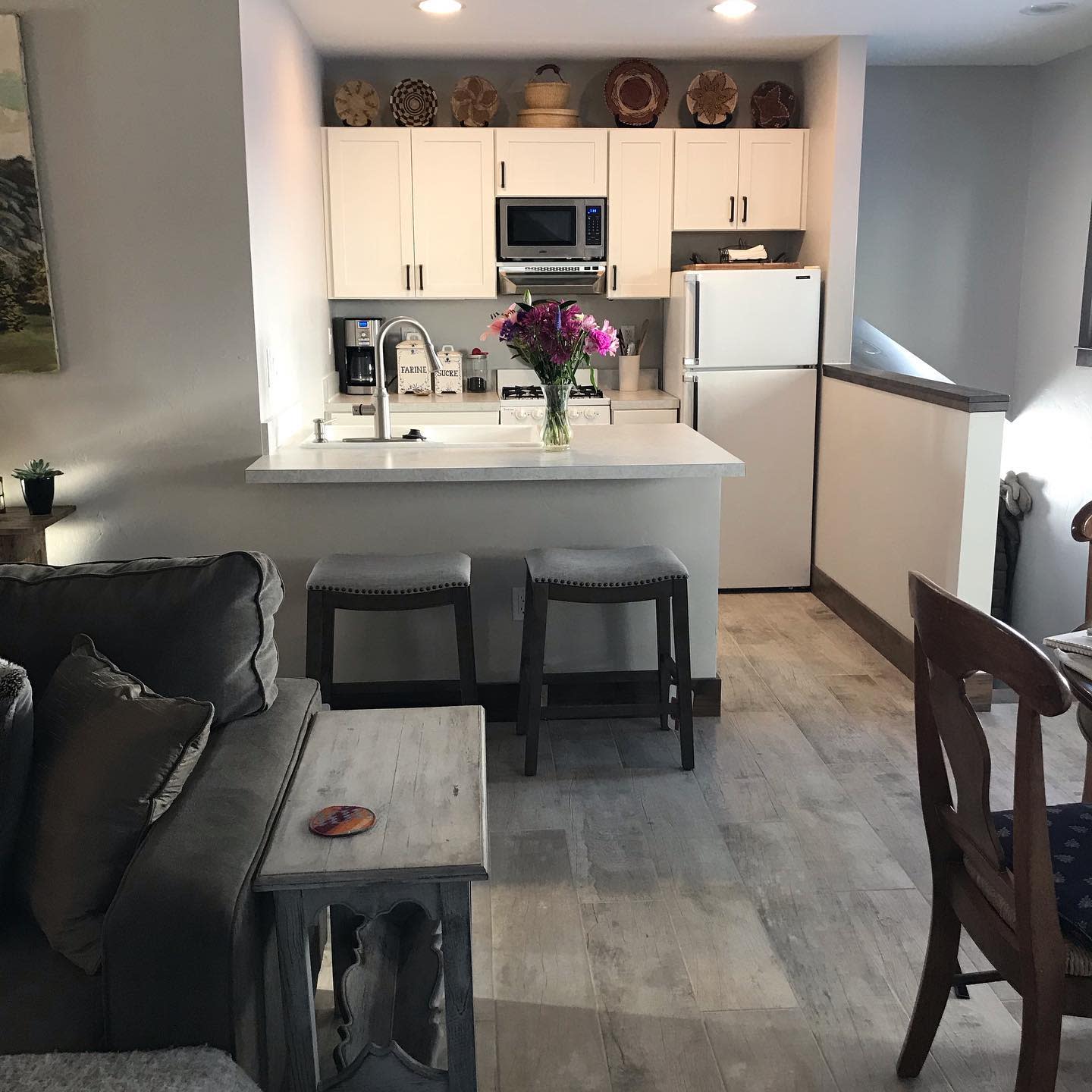 open kitchen living room small apartment white cabinets gray couch wood flooring